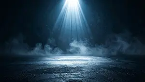 暗闇の中で青いスポットライトが地面を這う濃い霧を照らしているミステリアスなステージ