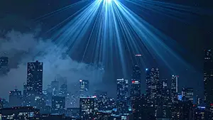 高層ビル群の夜景の上空から青い光のシャワーが街全体に降り注いでいる幻想的な都市風景