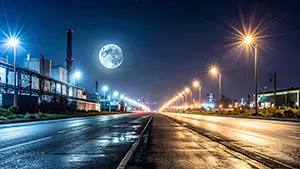 夜の工場地帯の道路を街灯が照らし空には大きな満月が輝いているインダストリアルな風景